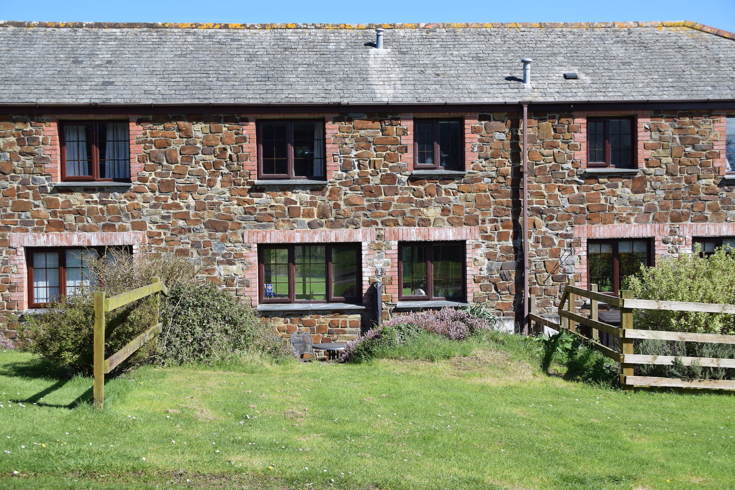Back garden of Glen Vally Holiday Cottage looking to cottage with stone and brick wall and 4 windows